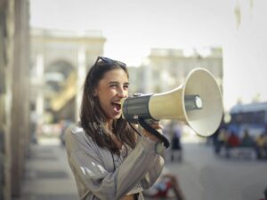 cheerful young woman screaming into megaphone