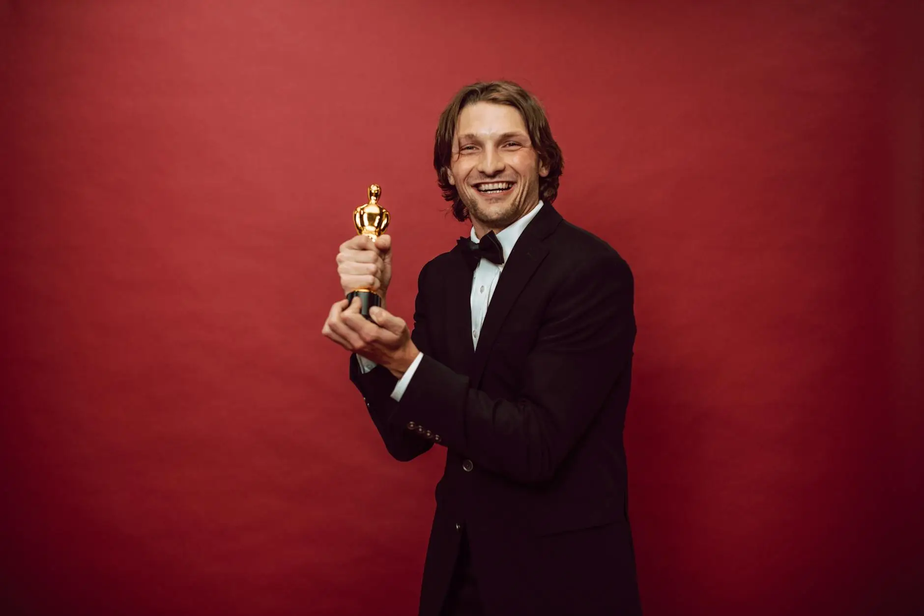 Um homem feliz vestindo um terno preto e segurando seu troféu